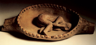 Статуэтка человека в эмбриональной позе, лежащего внутри лягушки