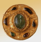 Золотая, круглая фибула на бронзовой основе: цветными вставками и сканным узором